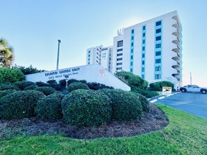 A hotel sign with "Island Winds East" and "33 West Beach Blvd." The building is white with blue accents and has multiple floors.