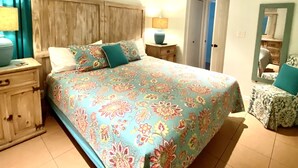Une chambre à coucher avec un lit, une table de chevet, un ventilateur de plafond et une porte.