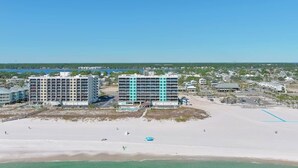 Un hôtel situé en bord de mer, composé de plusieurs bâtiments, avec une plage de sable fin et un ciel dégagé.