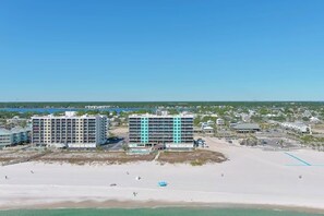 Un hôtel situé en bord de mer, composé de plusieurs bâtiments, avec une plage de sable fin et un ciel dégagé.