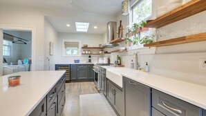 Una cucina moderna con mobili grigi, un piano di lavoro bianco e un lucernario.