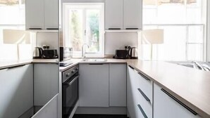 Una cocina moderna con armarios blancos, una estufa y un lavamanos.
