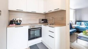 Cocina compacta con alacenas blancas, microondas, fregadero y estufa.