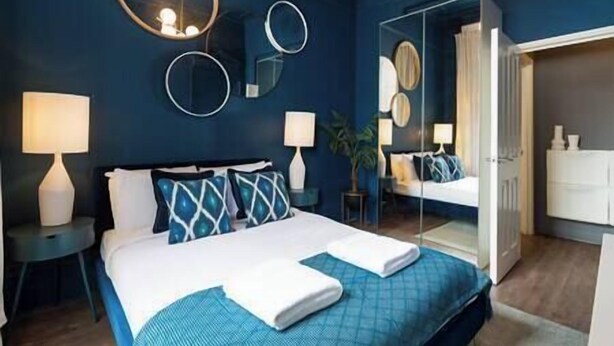 A hotel room with a bed, bedside tables, a mirror, and a wardrobe.