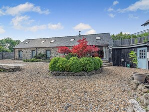 A stone house with a gravel driveway and a small garden with red foliage. - 2 bedroom accommodation in Taliaris, near Llandeilo (Taliaris, near Llandeilo)
