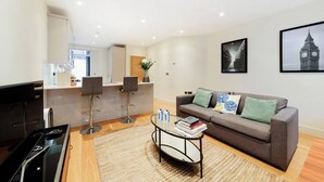 Ein modernes Wohnzimmer mit Sofa, Couchtisch und einer Küche im Hintergrund.