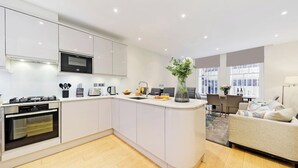 Une cuisine moderne avec des meubles blancs, un four encastré et un îlot central.