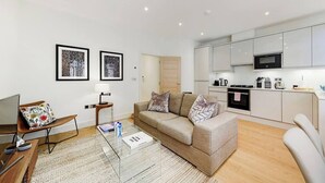 A modern living room with a sofa, coffee table, and framed artwork on the wall. - PBC | Luxury One Bedroom Apartment in Central London, Fitzrovia GT8 (London)