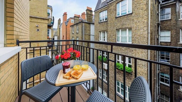 A balcony with a table set for breakfast, featuring toast, jam, and orange juice. - PBC | Modern One Bedroom Apartment in Soho GT8 (London)