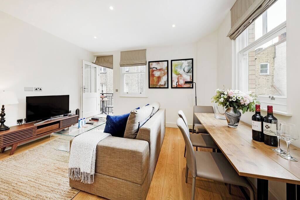A modern living room with a sofa, TV, and dining area with a table and chairs.