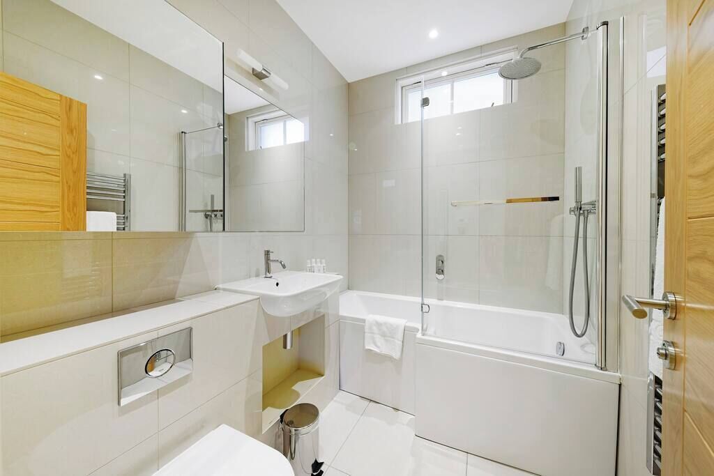 A modern bathroom with a glass-enclosed shower, a sink, and a mirror.