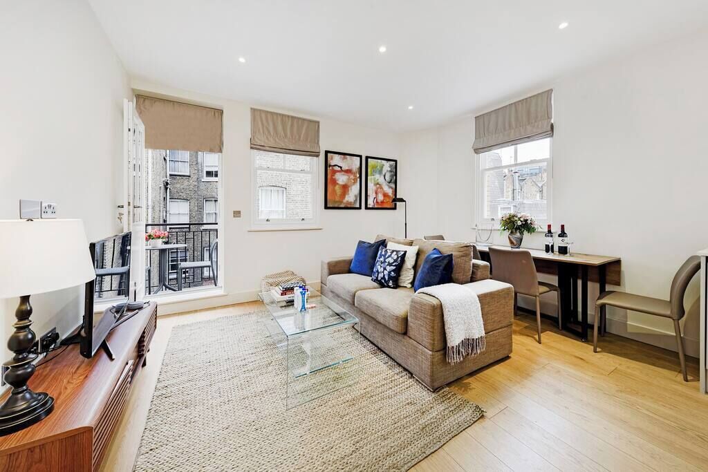 A modern living room with a sofa, coffee table, and a dining area.