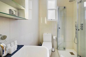Ein modernes Badezimmer mit einer Duschkabine aus Glas, einer weißen Toilette und einer Badewanne.