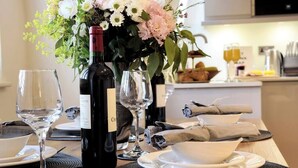 Une table à manger dressée avec des verres à vin, une bouteille de vin et un centre de table floral.