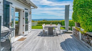 A wooden deck with a table and chairs, a barbecue grill, and a view of the ocean. - Drift @ 5 Mile Bay (Taupo)
