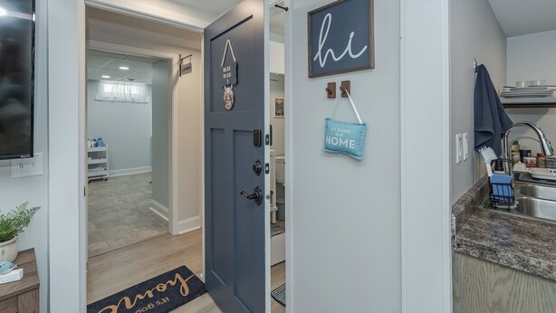 A modern kitchen with a sink, countertop, and a door leading to a hallway.