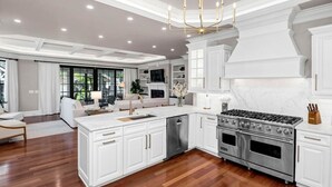 Una cocina amplia con armarios blancos, estufa de acero inoxidable y horno empotrado.