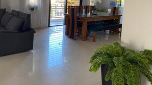 Zona d'estar àmplia amb sofà, taula de dinar amb cadires, planta en test i ventilador de sostre.
