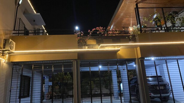 Un edifici modern amb un balcó, grans finestres i un cotxe estacionat al fons.