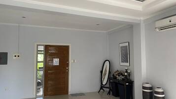 Un pasillo espacioso con una puerta de madera, un cuadro enmarcado en la pared y dos jarrones grandes sobre una mesa.