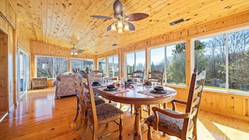 Une salle à manger en bois avec une grande table, des chaises et un ventilateur de plafond.