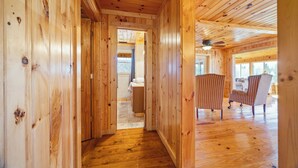 Interior de madera con un pasillo que lleva a una habitación con cama y una silla.