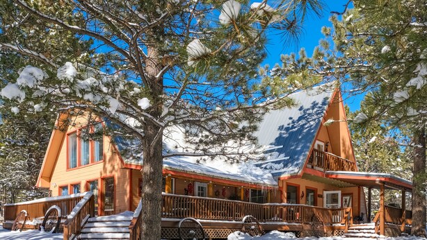 A cabin with a steep roof, wooden exterior, and a porch with a railing. - Charming 3-bedroom cabin with WiFi in Angel Fire (Angel Fire)