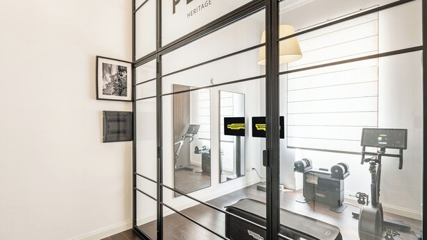A modern interior with a glass partition, a treadmill, and exercise equipment.