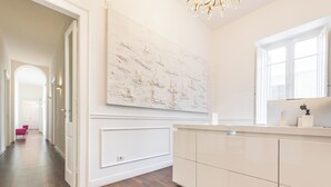 A modern kitchen with a large white cabinet, a marble backsplash, and a wooden floor.