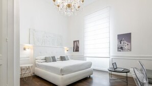 A modern bedroom with a large bed, a chandelier, and artwork on the walls.