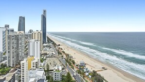 A coastal cityscape with high-rise buildings, a sandy beach, and a clear blue sky.
