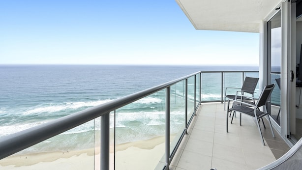 Ein Balkon mit Meerblick, ausgestattet mit zwei Stühlen und einer Glasufernung.