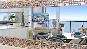 Ein moderner Essbereich mit Blick auf die Stadtlandschaft, einem großen Flachbildfernseher und einem Balkon mit Geländer.