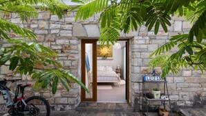 Un bâtiment en pierre avec un lit, un vélo et une étagère pour les plantes.