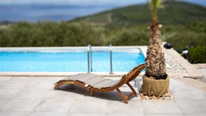 Un espace aménagé au bord de la piscine, avec un fauteuil de relaxation et une plante en pot.