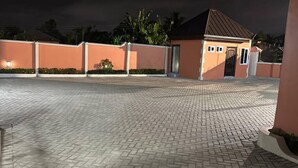 A paved driveway leading to a building with a brown roof and a door. - Senalli Hotel (Koforidua)