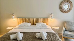A hotel room with a bed, two bedside tables, a chair, and a wall-mounted mirror.