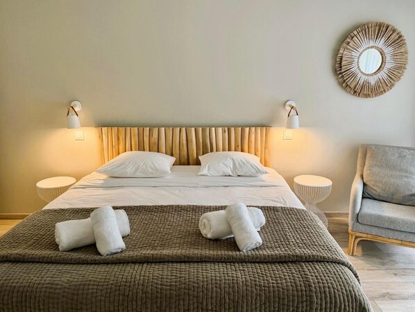 Une chambre d’hôtel avec un lit, deux tables de chevet, une chaise et un miroir fixé au mur.