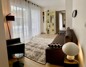 Ein modernes Wohnzimmer mit einer Couch, einer Lampe, einem Klavier und einem Bücherregal.