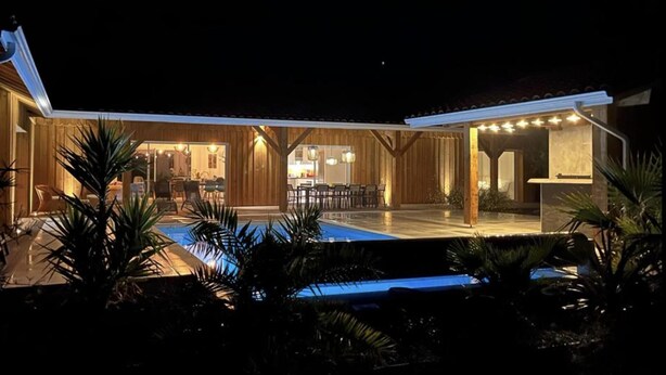 A modern outdoor pool area with a dining area and a covered seating space.