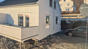A white building with a balcony, a car parked nearby, and a satellite dish on the roof. - Beach front home in Frosta with WiFi (Frosta)