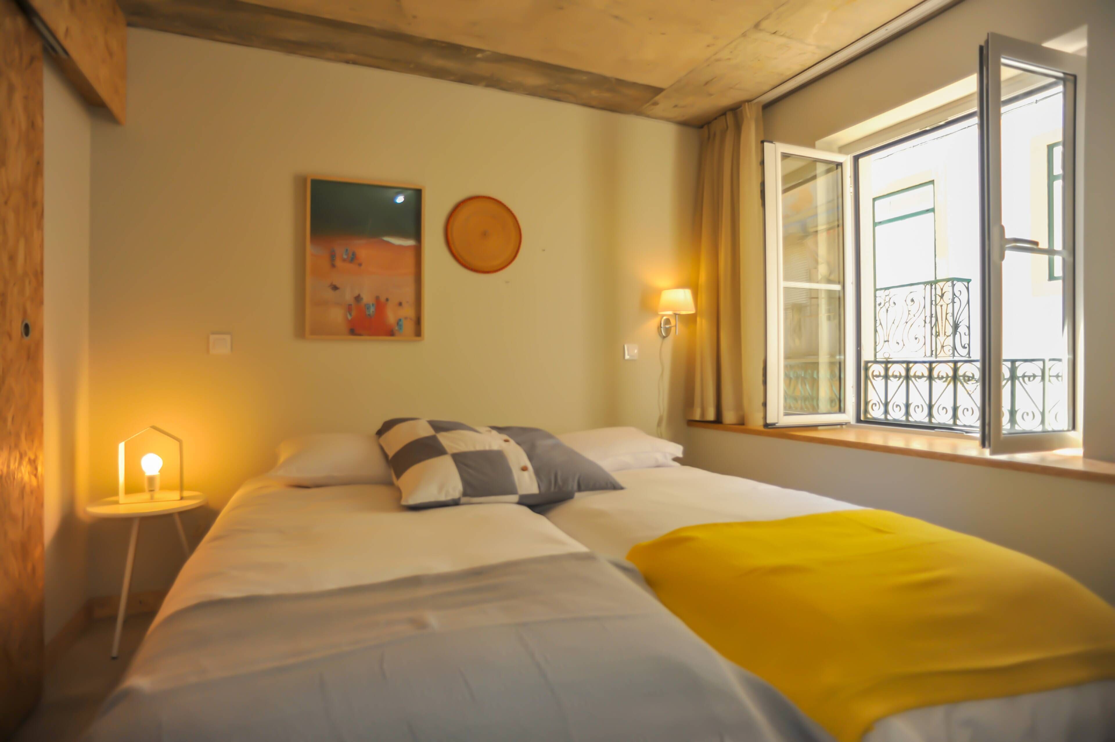 Een hotelkamer met een bed, een bedlampje, een schilderij aan de muur en een balkon met raam.