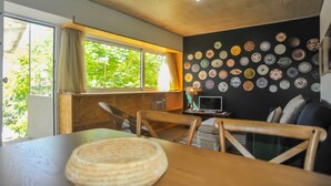 Una habitación acogedora con techo de madera, una mesa de comedor con sillas, un televisor y una pared decorada con diferentes platos.