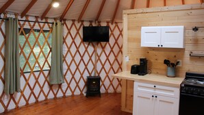 Une cuisine chaleureuse avec un poêle en bois, une machine à café et des placards.