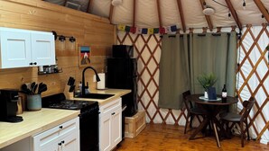 Une cuisine chaleureuse avec des meubles de rangement en bois, une cuisinière et un coin repas comprenant une table et des chaises.
