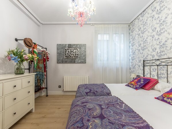 Un dormitorio con cama, cómoda y candelabro.
