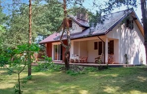 A house with a covered porch, a dining area with chairs, and a small table.