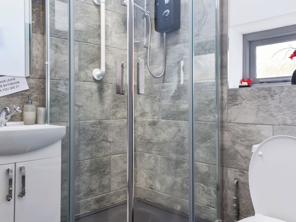 A modern bathroom with a glass-enclosed shower, a white sink, and a toilet.