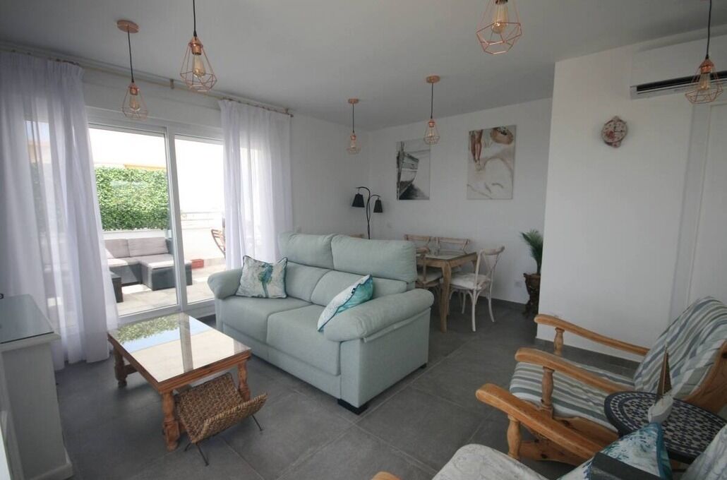 Un salon chaleureux avec un canapé bleu clair, une table basse en bois et un coin repas comprenant une petite table et des chaises.