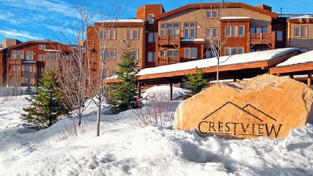 A snow-covered landscape with a large rock bearing the word "CRESTVIEW" and a multi-story building with balconies and windows.